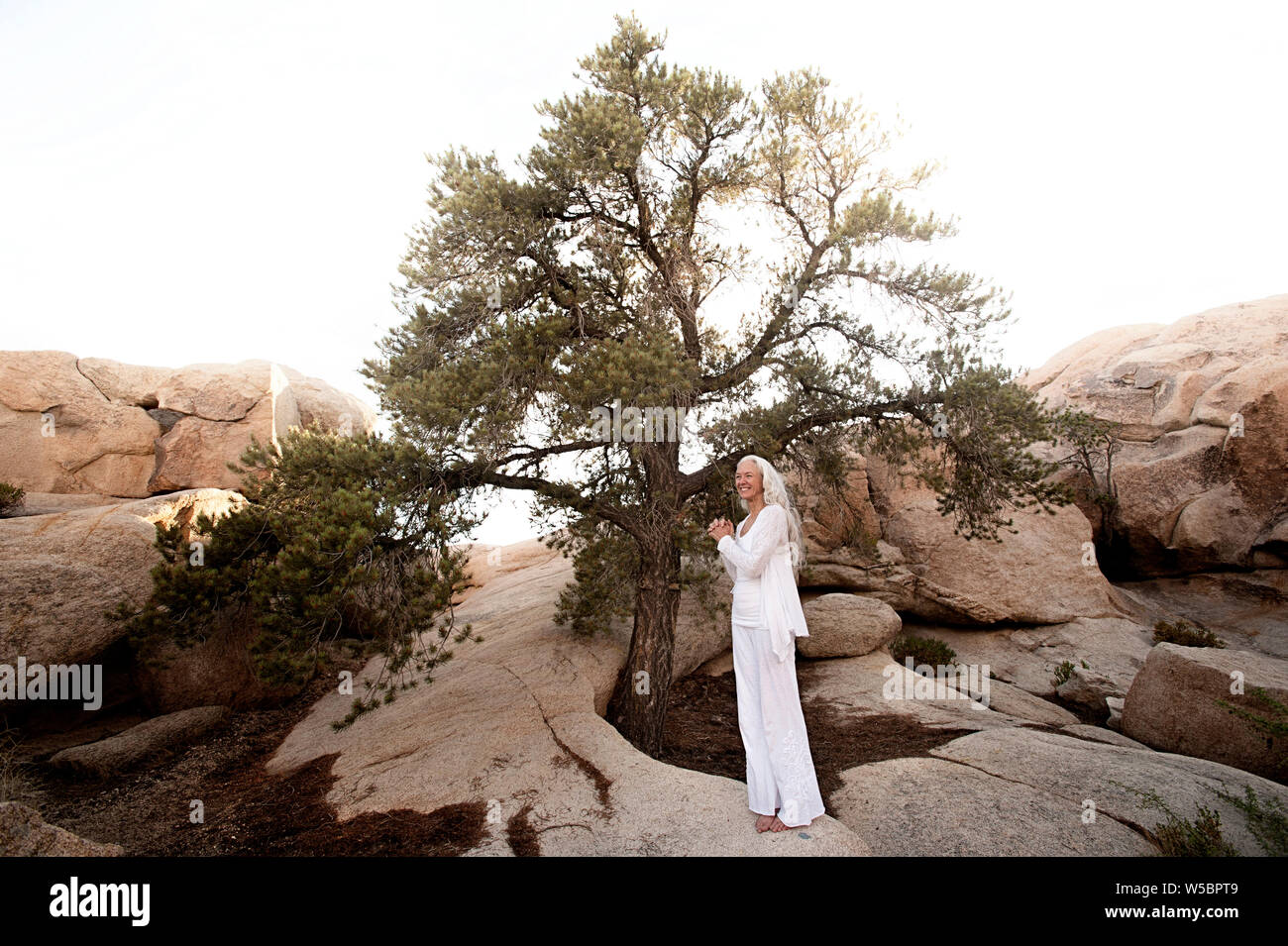 Bella coppia spirituale della donna yoga earing bianco in un deserto naturale paesaggio naturale in piedi sotto un albero bellissimo. Foto Stock