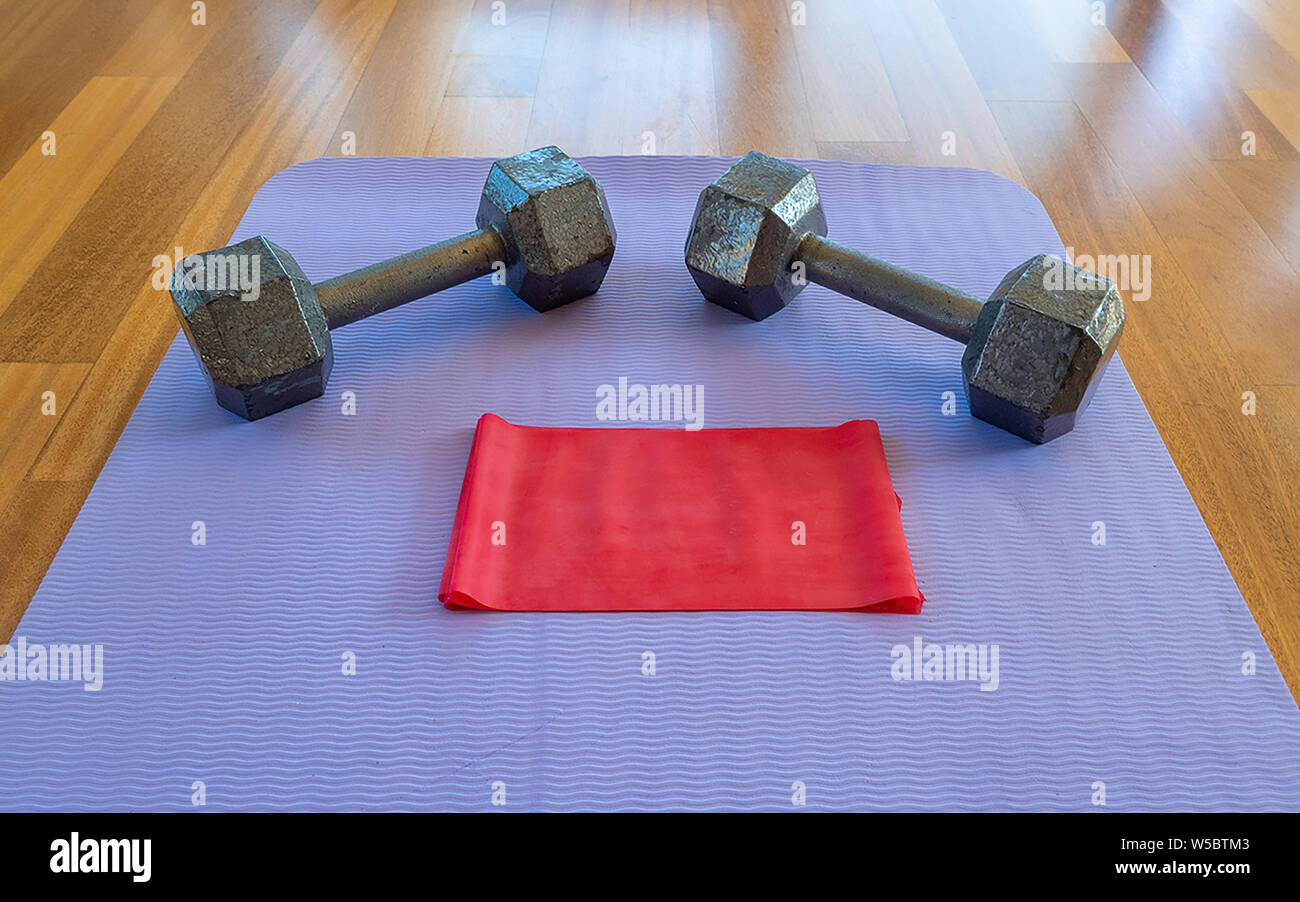 Close up di pesi e di esercizio della banda su un materassino yoga per un allenamento domestico Foto Stock