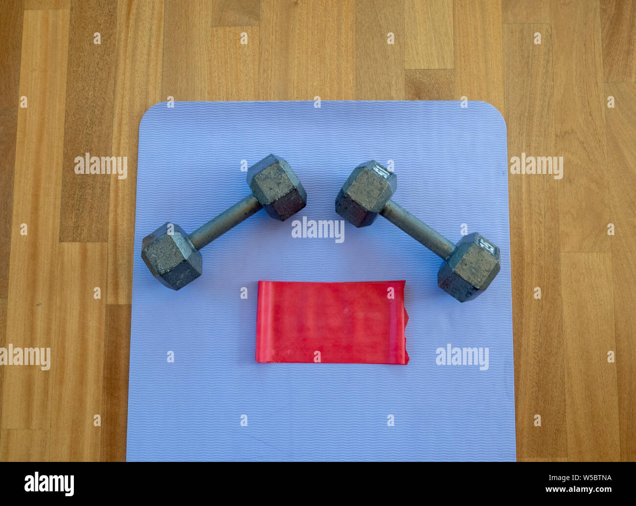 Manubri e banda di esercizio su un materassino yoga per un allenamento domestico Foto Stock