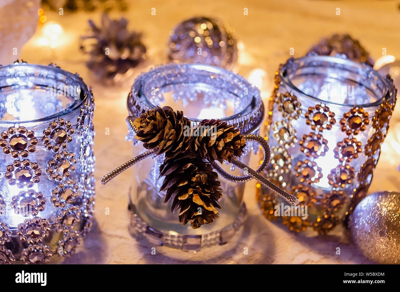 Il Natale porta candele decorate con argento e oro con pietre calde luci e pigne Foto Stock