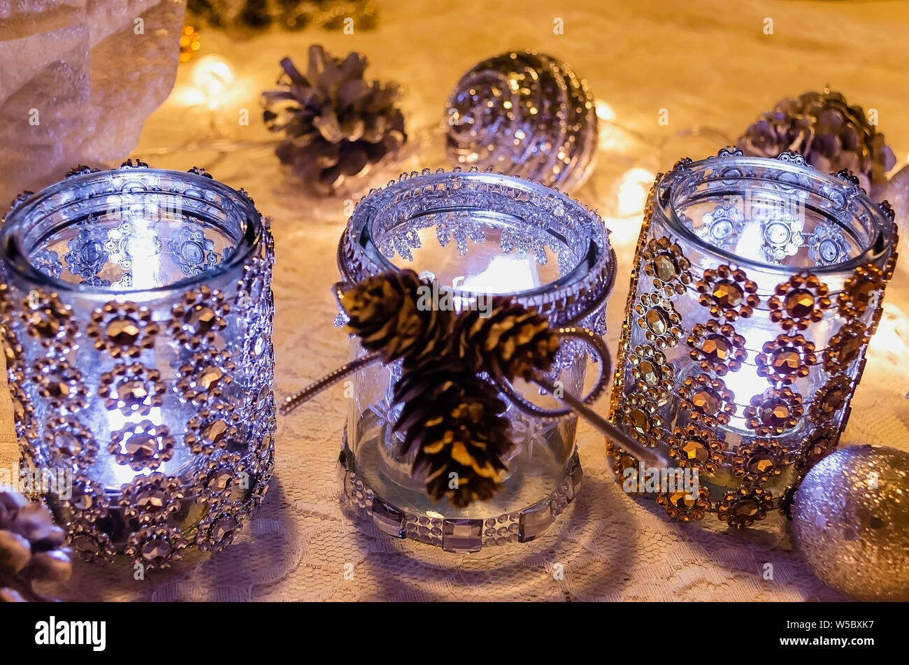 Il Natale porta candele decorate con argento e oro con pietre calde luci e pigne Foto Stock