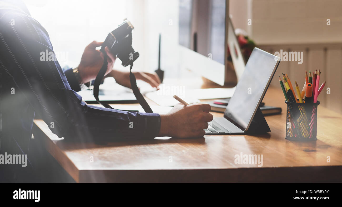 Giovani Fotografi a lavorare sui loro progetti con la compressa in un moderno ufficio creativo Foto Stock