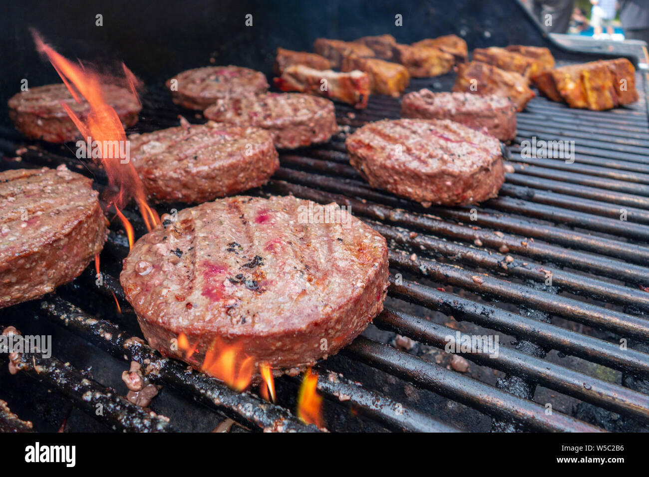 Hamburger e costolette di agnello cottura su una calda gass outdoor grill Foto Stock