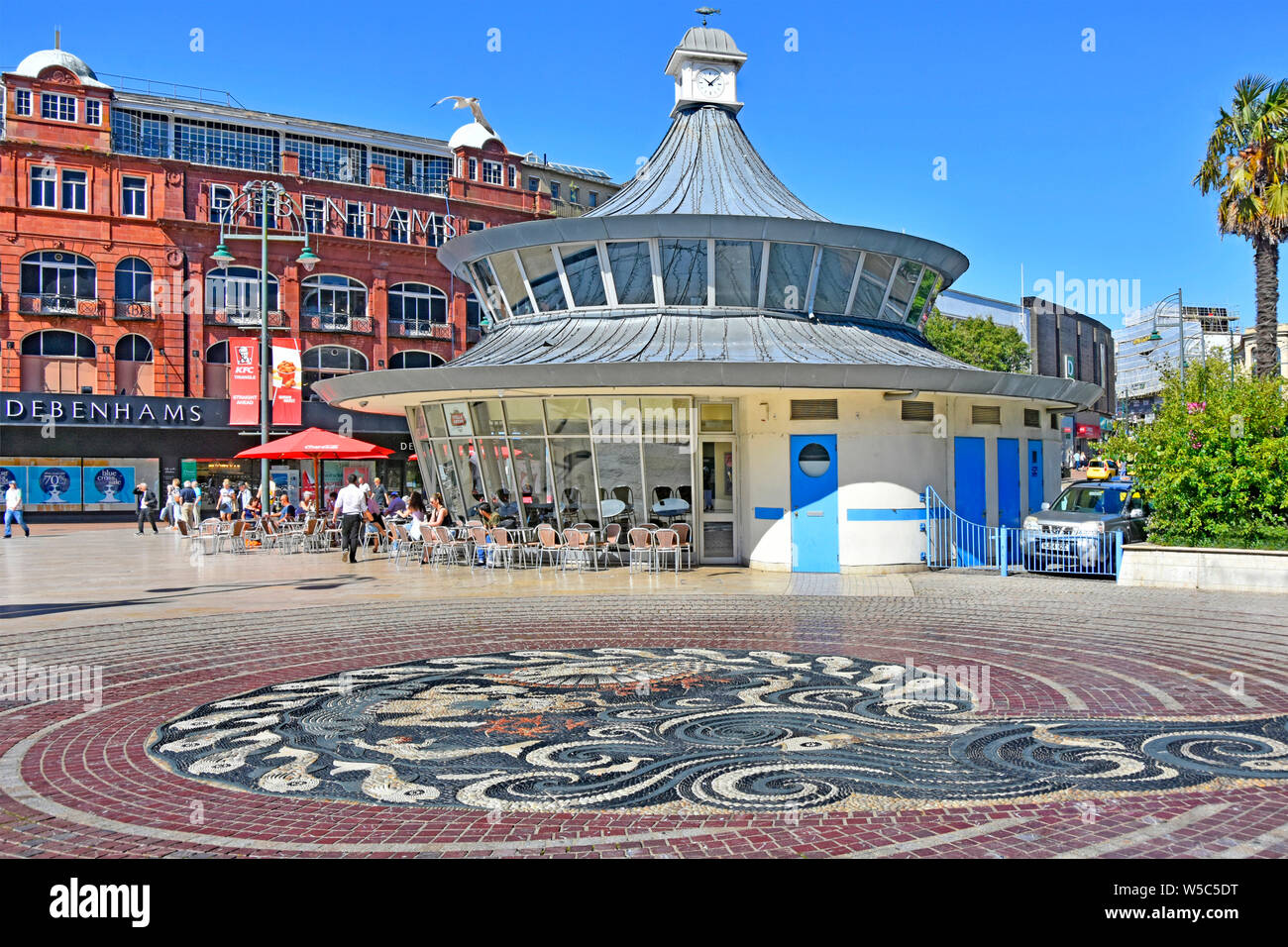 Centro di Bournemouth la piazza e mosaico di ciottoli nella pavimentazione con negozio Debenhams & persone seduti all'aperto a Obscura street cafe Dorset England Regno Unito Foto Stock