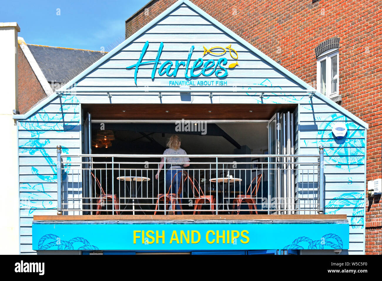 Negozio di fish and chips cafe Harlees business al primo piano, ristorante con balcone all'aperto e cameriera che lavora con vista su Poole Harbour Dorset England UK Foto Stock