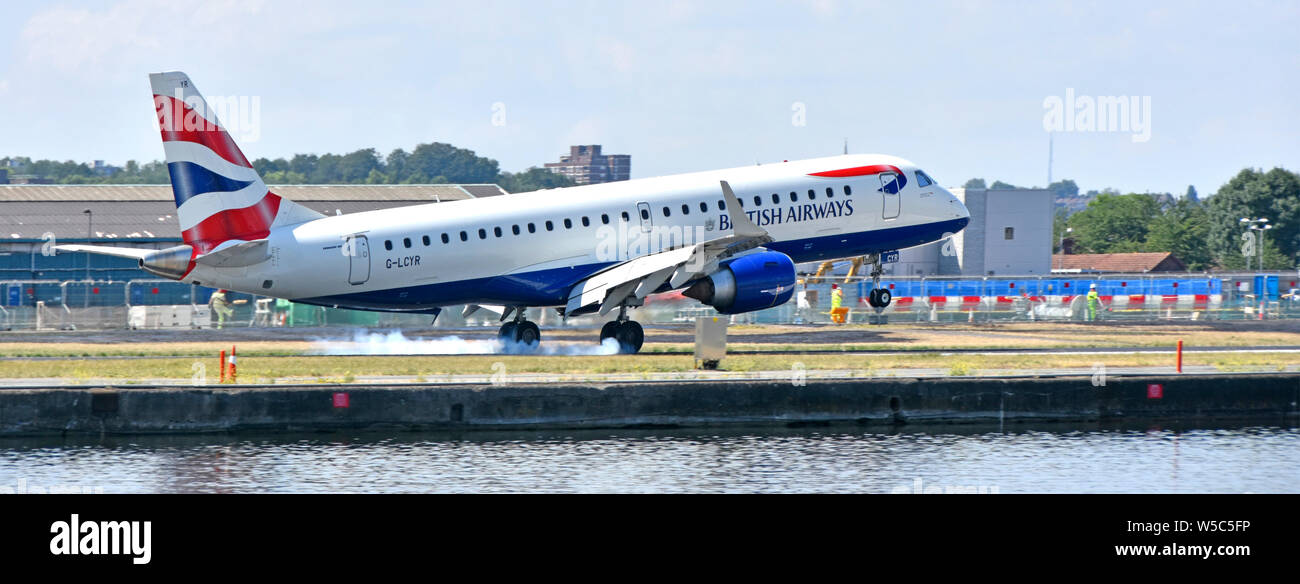 British Airways piano in atterraggio a London City Airport BA Cityflyer Embraer 190SR G-LCYR bruciando i pneumatici in gomma su touchdown nei Docklands di Londra REGNO UNITO Foto Stock