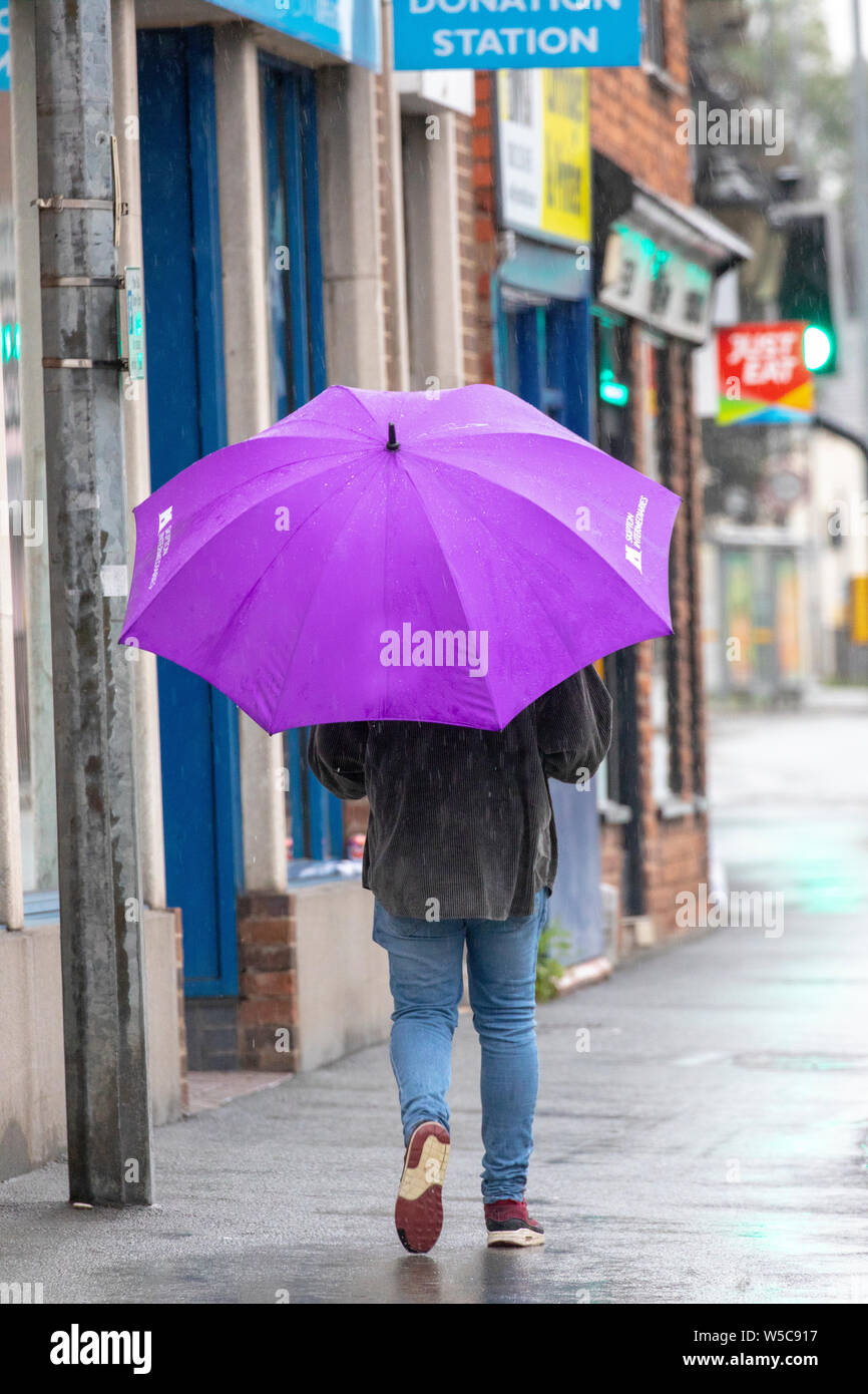A nord-ovest, UK. Regno Unito: Meteo Domenica 28 luglio 2019. Un tempo parte anteriore si muove lentamente attraverso il paese oggi da Nord con le temperature dello scambiatore di calore e heavy rain per alcuni come esso si muove lentamente attraverso il Regno Unito come questo pedone scoperto sotto un grande ombrello nella città di Chester, Cheshire © DGDImages/AlamyNews Foto Stock