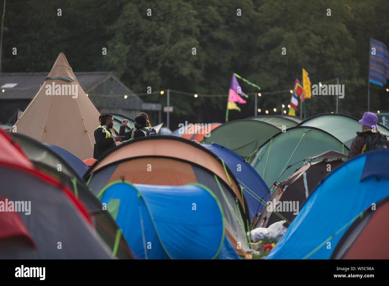 WOMAD Festival, Charlton Park, Wiltshire, Regno Unito. Il 28 luglio 2019. La domenica mattina presto scene a WOMAD, tra le 05:30-06:30, con late night festaioli stare sveglio fino alle prime ore del mattino, night-shift e della sicurezza dei lavoratori e i mattinieri che ha battuto la doccia code. Credito: Francesca Moore/Alamy Live News Foto Stock