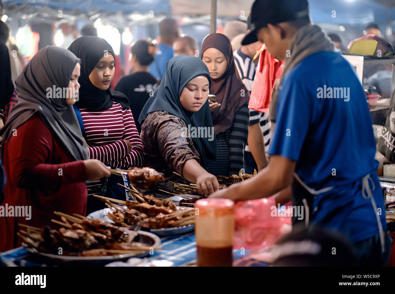 Il Langkawi, Malesia - LUG 2019: Asian womens scegli il cibo sulla strada del mercato. Unidentified popoli asiatici vendere il cibo al mercato notturno di strada a piedi. Tradizione Foto Stock