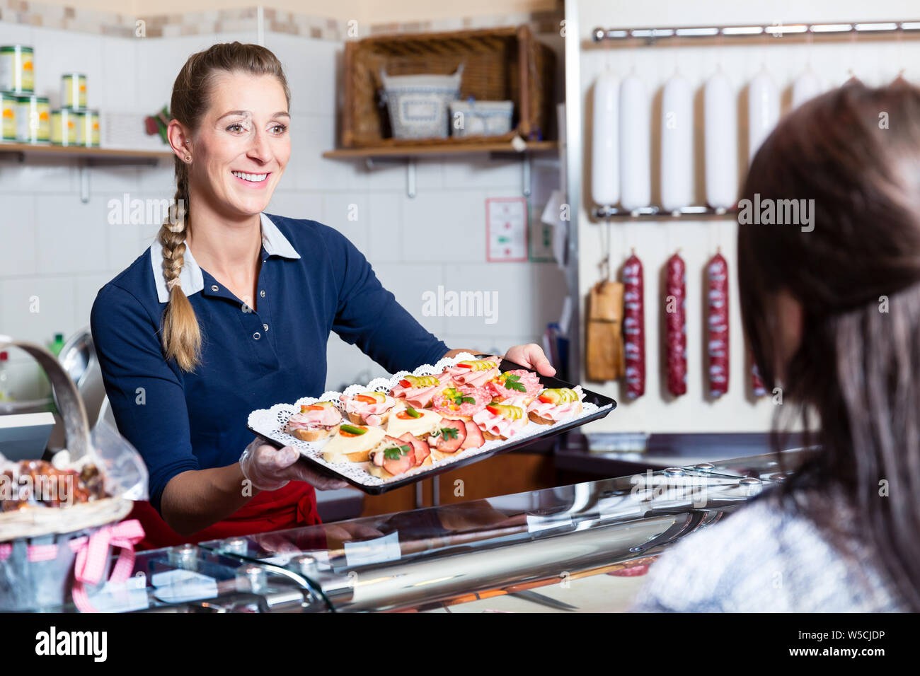 Donna di vendite nel negozio di macellaio offre finger food Foto Stock