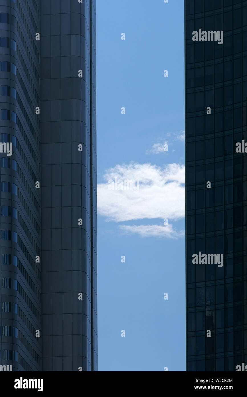 Una nuvola e il cielo blu tra gli angoli e i bordi laterali di due moderni grattacieli. Foto Stock