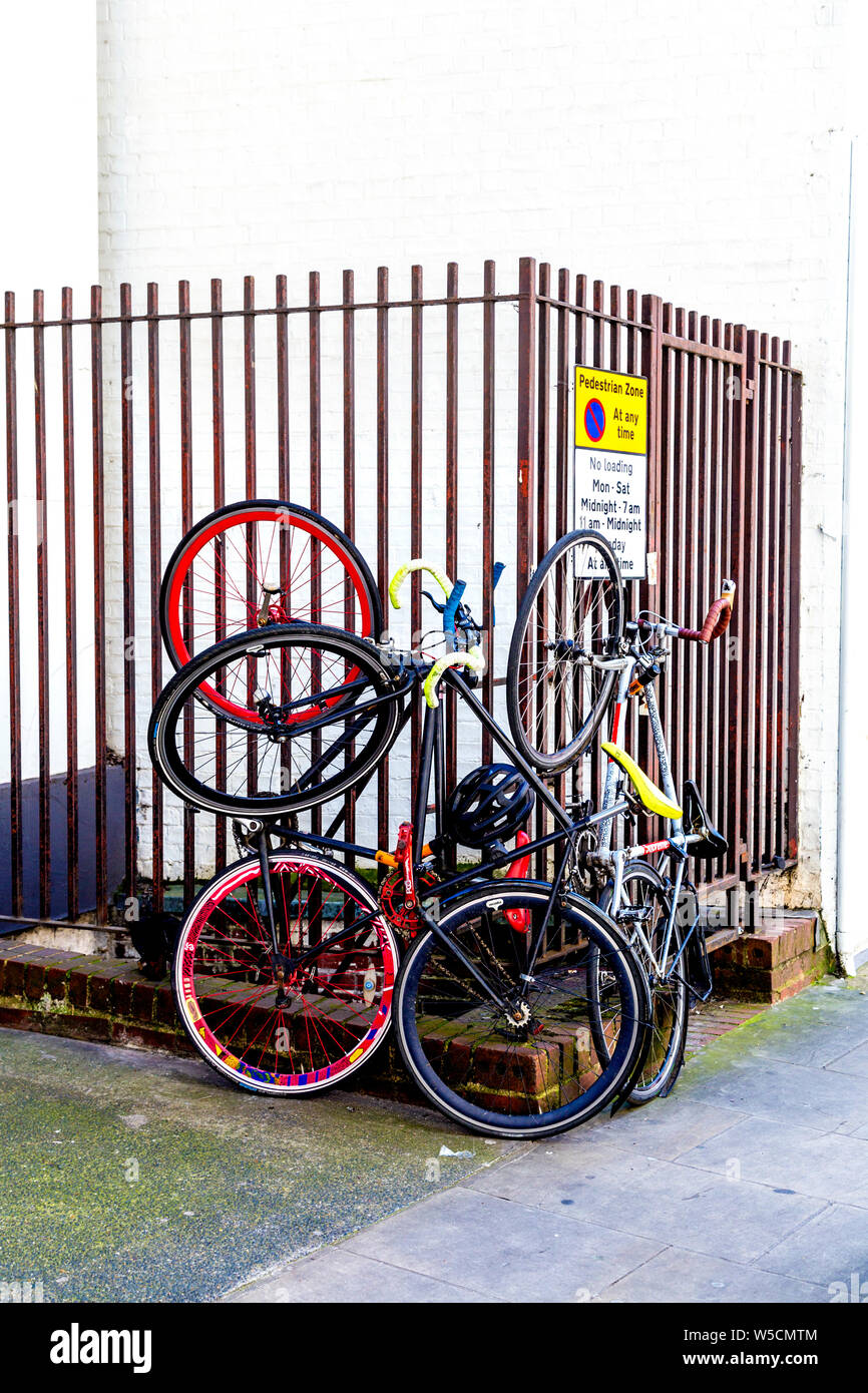 Biciclette incatenato ad una ringhiera verticalmente, Soho, London, Regno Unito Foto Stock