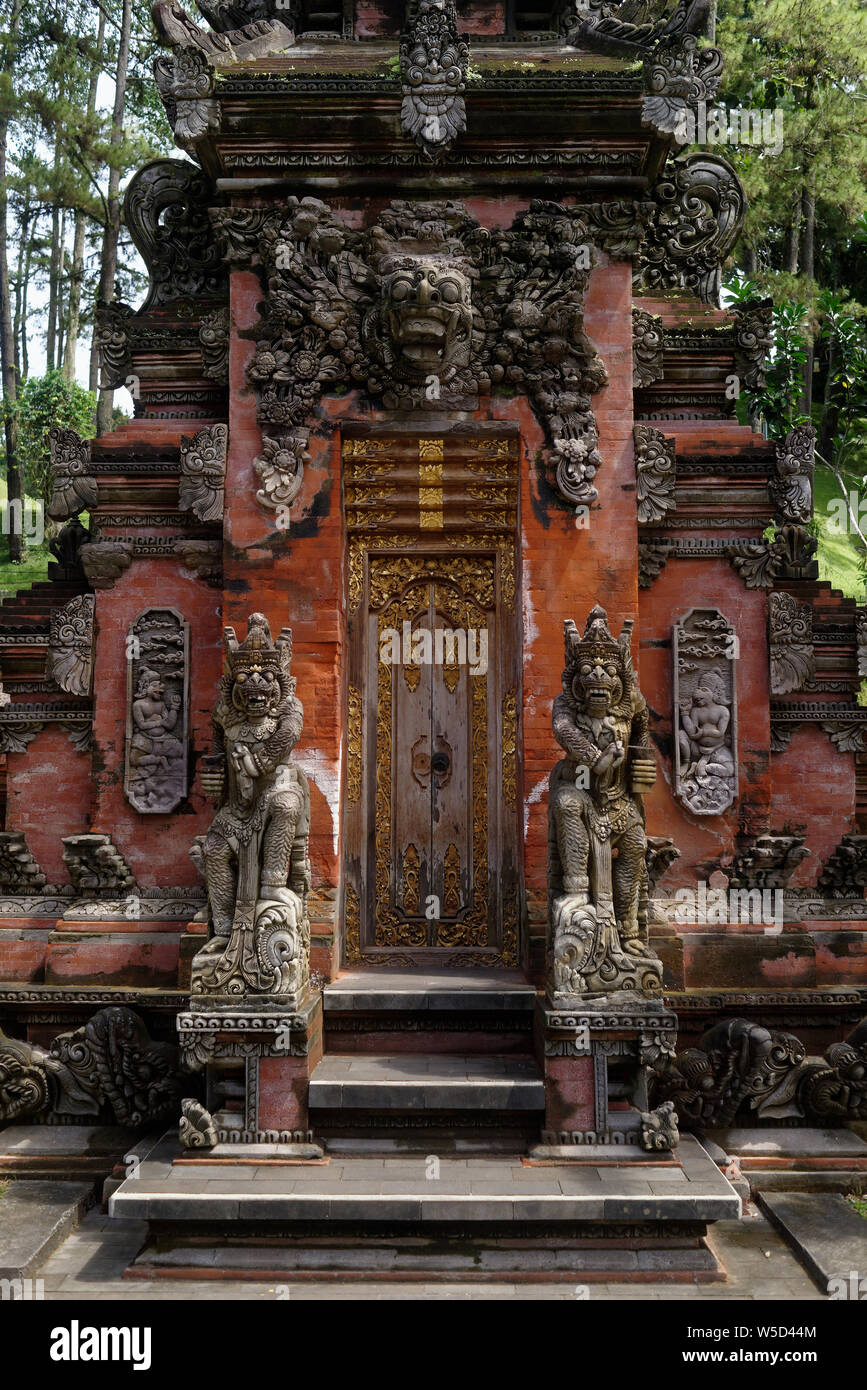 Grande e decorata in legno porte di entrata e pietra Bedogol come protettori, Ubud, Bali, Indonesia Foto Stock