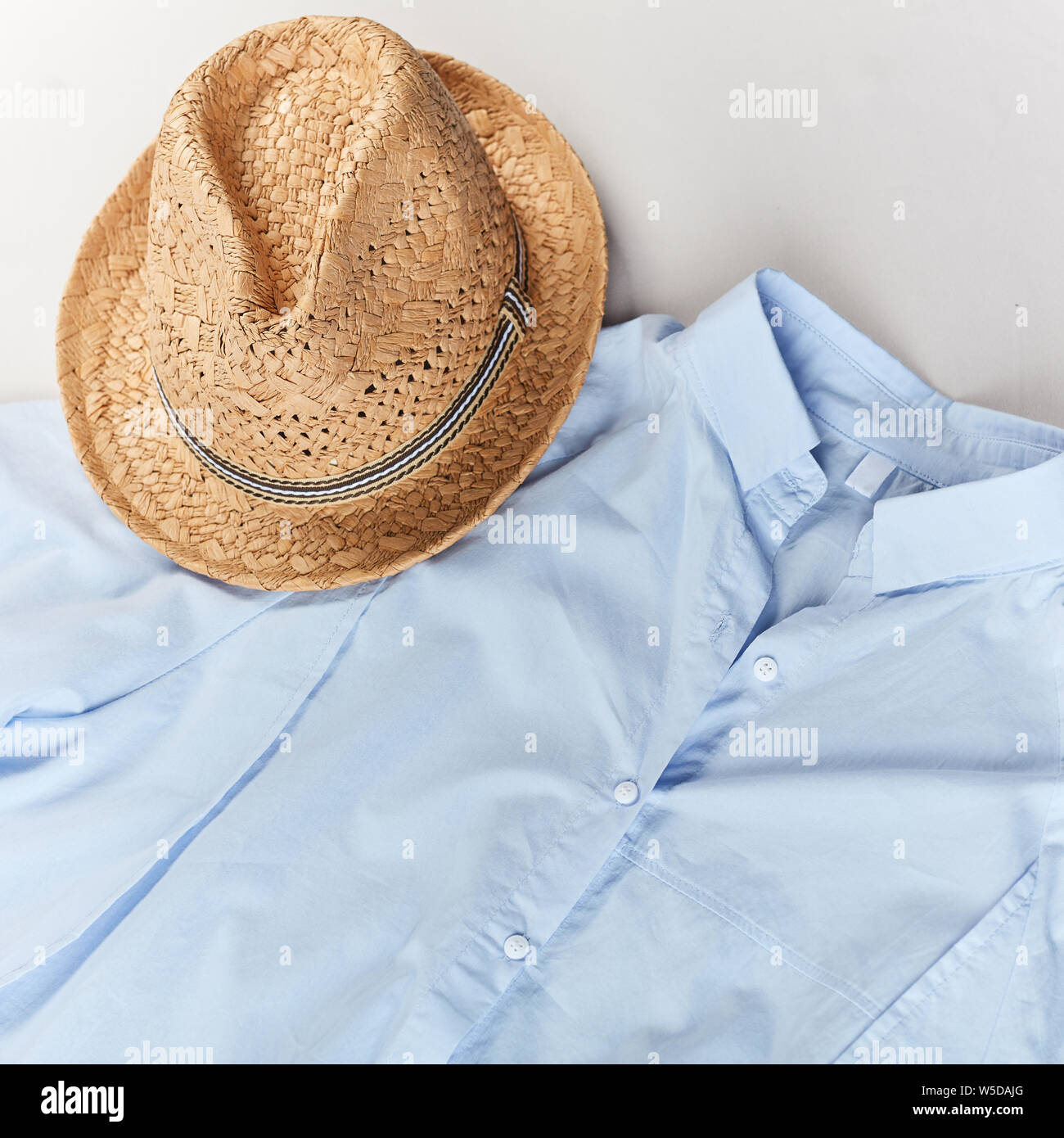 Annuncio di un elegante cappello di paglia. hat e luce maglietta blu su  sfondo bianco.shopaholic affare concetto Foto stock - Alamy