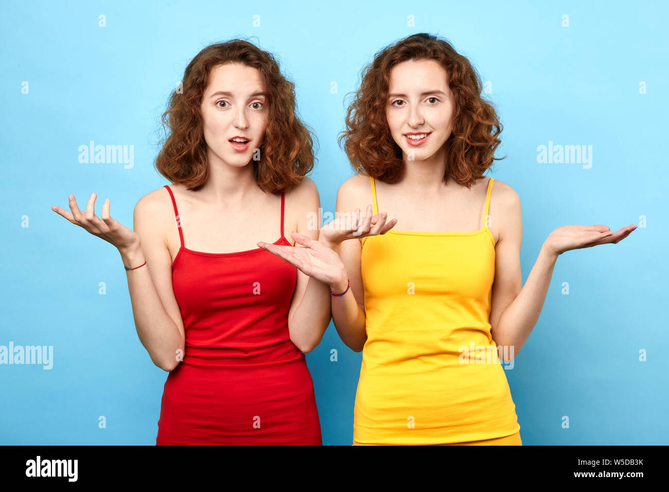 Ritratto di un perplesso esitato giovani gemelli scrollare le spalle isolate su sfondo blu. close up Foto.Non sappiamo Foto Stock