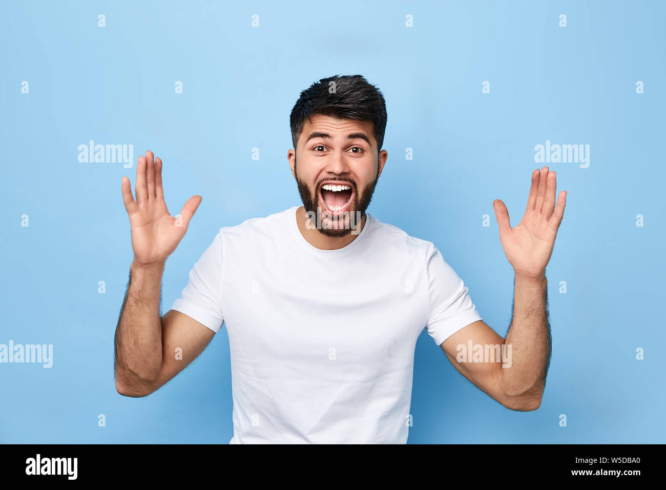 Funny Man con ampia bocca aperta dando una lotta, mettendo il vento fino. close up ritratto, isolato sfondo blu. l'uomo guarda la partita di calcio Foto Stock