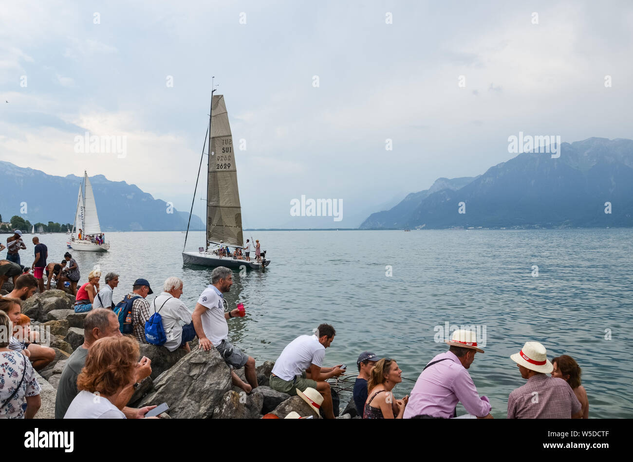 Vevey, Svizzera - 26 Luglio 2019: guardare la gente festante barche a vela durante la Fete des Vignerons 2019. Festa tradizionale omaggio alla tradizione viticola Lavaux nella regione dei vini. Una volta organizzati in 20-25 anni, una volta in una generazione, fin dal XVIII secolo. È stato onorato come il primo vivente tradizione in Svizzera a ricevuto riconoscimento UNESCO. Festival avrà luogo dal 18 luglio fino al 11 agosto 2019. Foto Stock