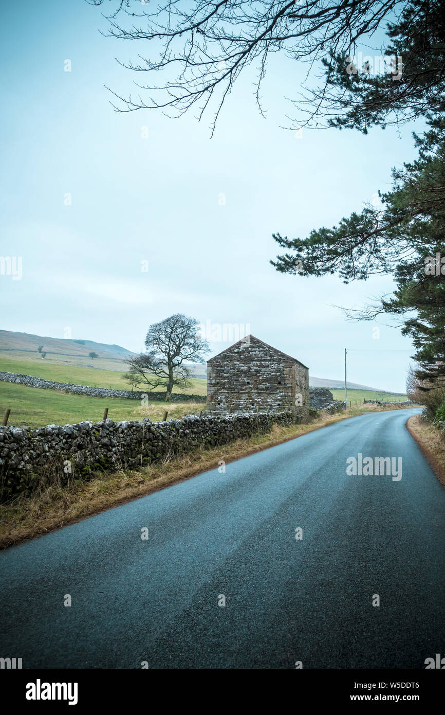 Il vecchio fienile in pietra a lato di una strada in Cumbria, England, Regno Unito Foto Stock