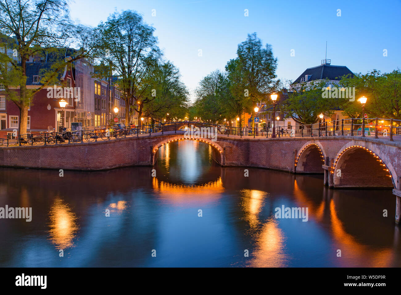 La riflessione di ponte lungo il canale in una notte a Amsterdam, Paesi Bassi Foto Stock