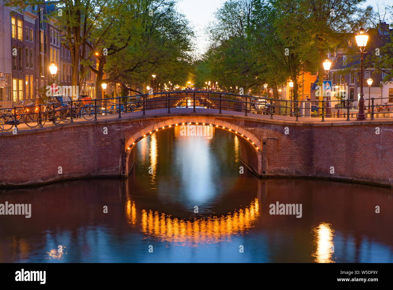 La riflessione di ponte lungo il canale in una notte a Amsterdam, Paesi Bassi Foto Stock