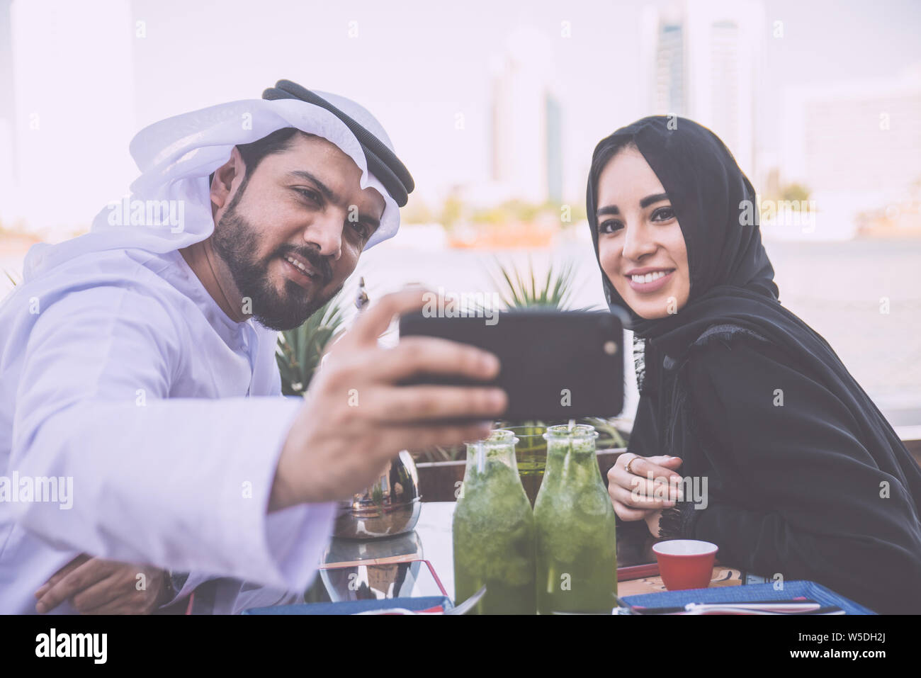 Coppia felice di trascorrere del tempo in Dubai. l uomo e la donna che indossa gli abiti tradizionali aventi una conversazione in un caffè Foto Stock