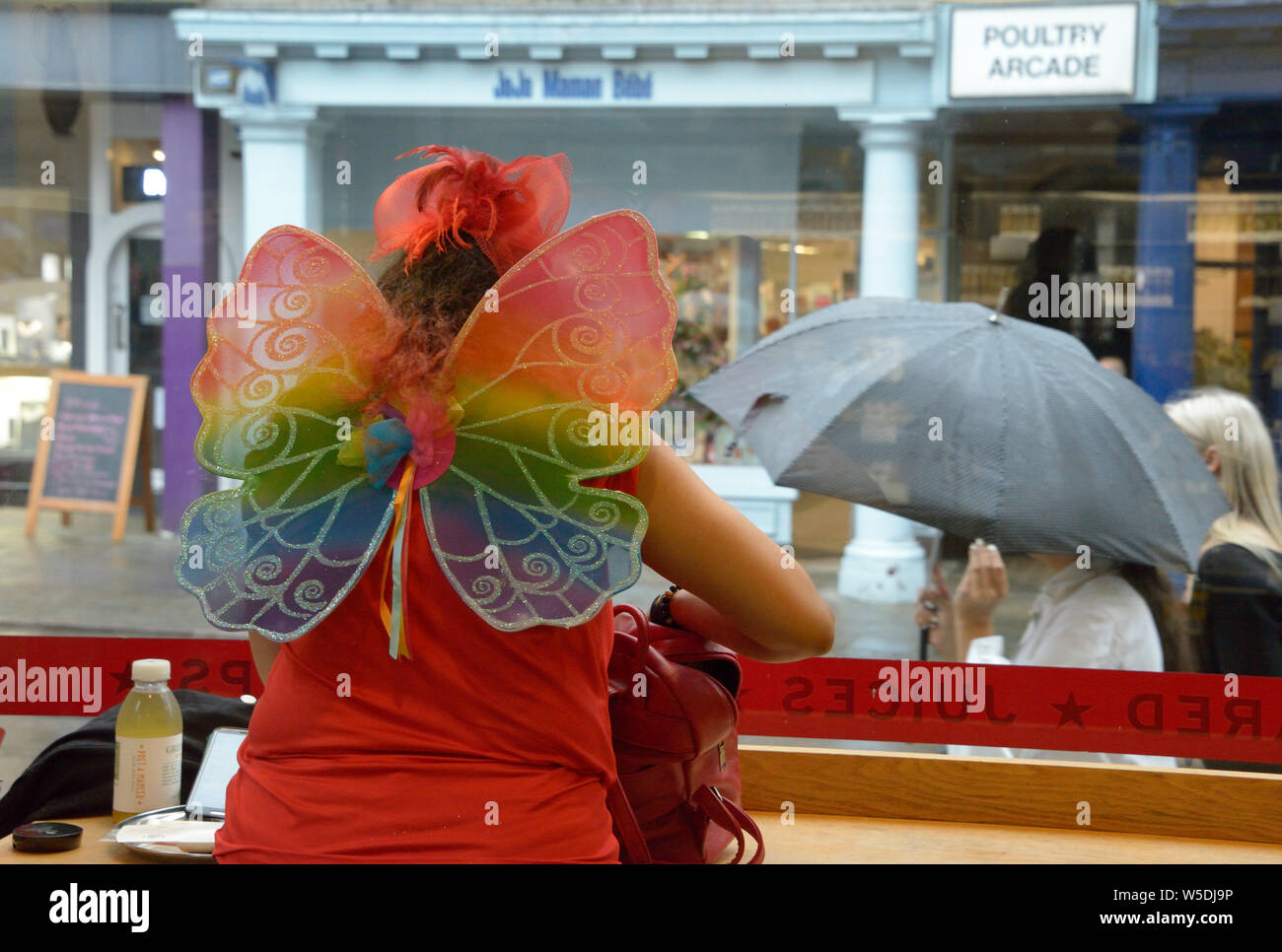 Donna con ali di farfalla, prendendo una pausa, al Pride evento Foto Stock