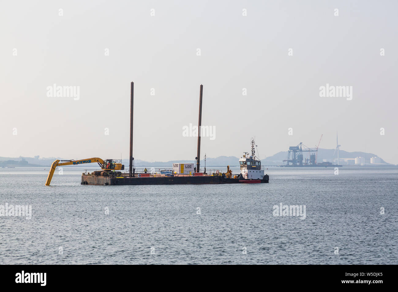 Una lunga portata di lavoro di scavo da una chiatta per installare un più tempesta schermato emissario nel Firth of Clyde, Largs, North Ayrshire, in Scozia, Regno Unito Foto Stock