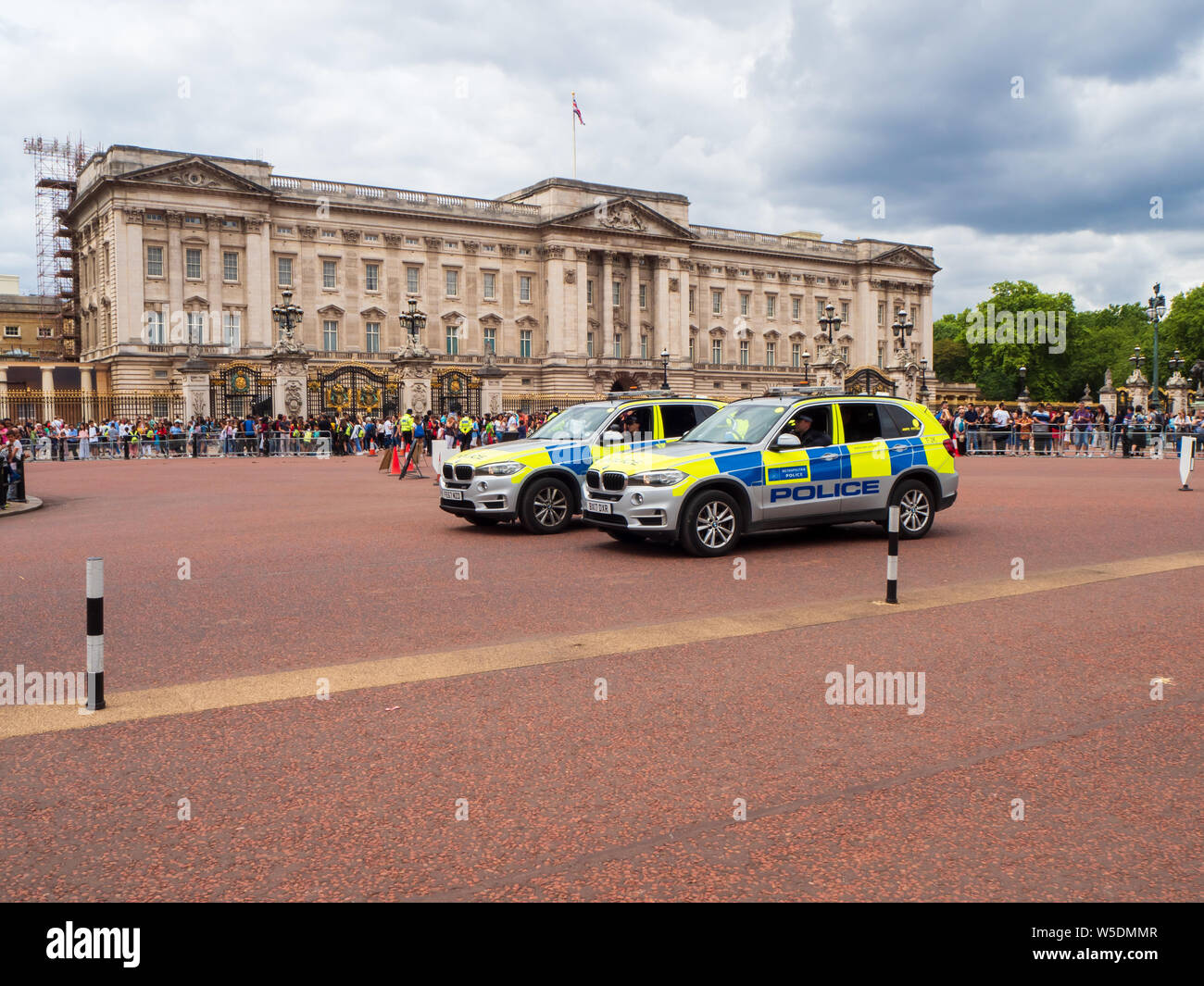 Due forze di polizia liveried battenberg BMW X5 automobili contenenti ufficiali armati pattugliano con Buckingham Palace in background Foto Stock