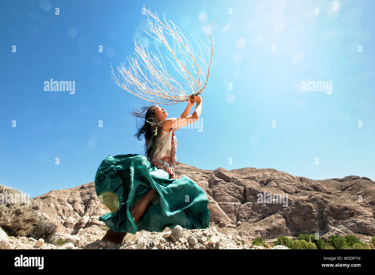 Bella asiatica spirituale Korean American woman dancing in cielo natura potentemente con un grande tumbleweed indigeni scheletro di piante vicine montagne. Foto Stock