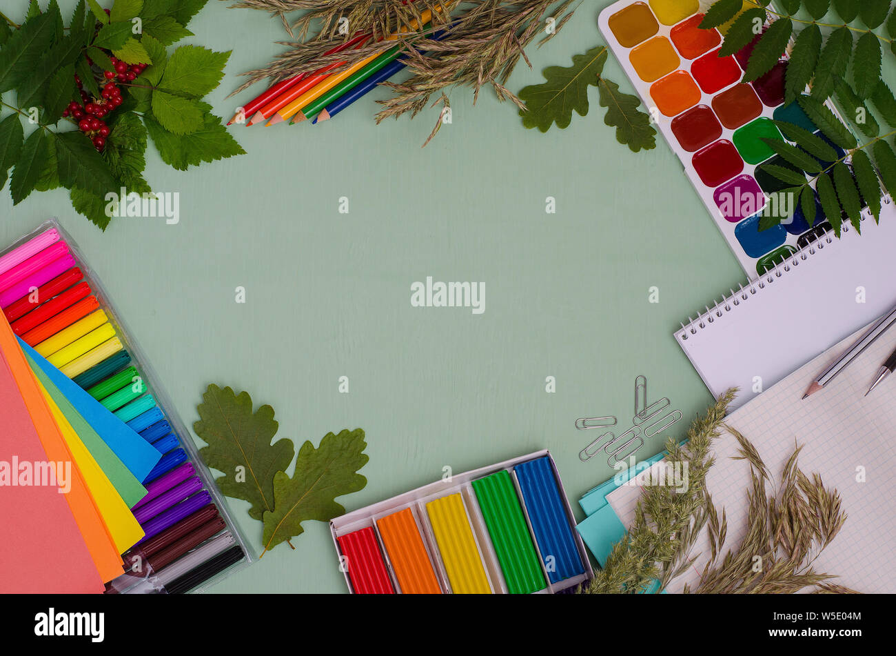 Si torna a scuola: composizione di forniture scolastiche e foglie con copia spazio su uno sfondo verde Foto Stock