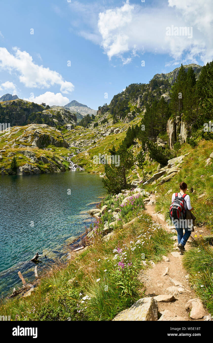 Escursionista femminile accanto a Estanh Major de Colomèrs a Aigüestortes i Estany de Sant Maurici National Park (Valle de Arán, Lleida, Pirenei, Catalogna, Spagna) Foto Stock