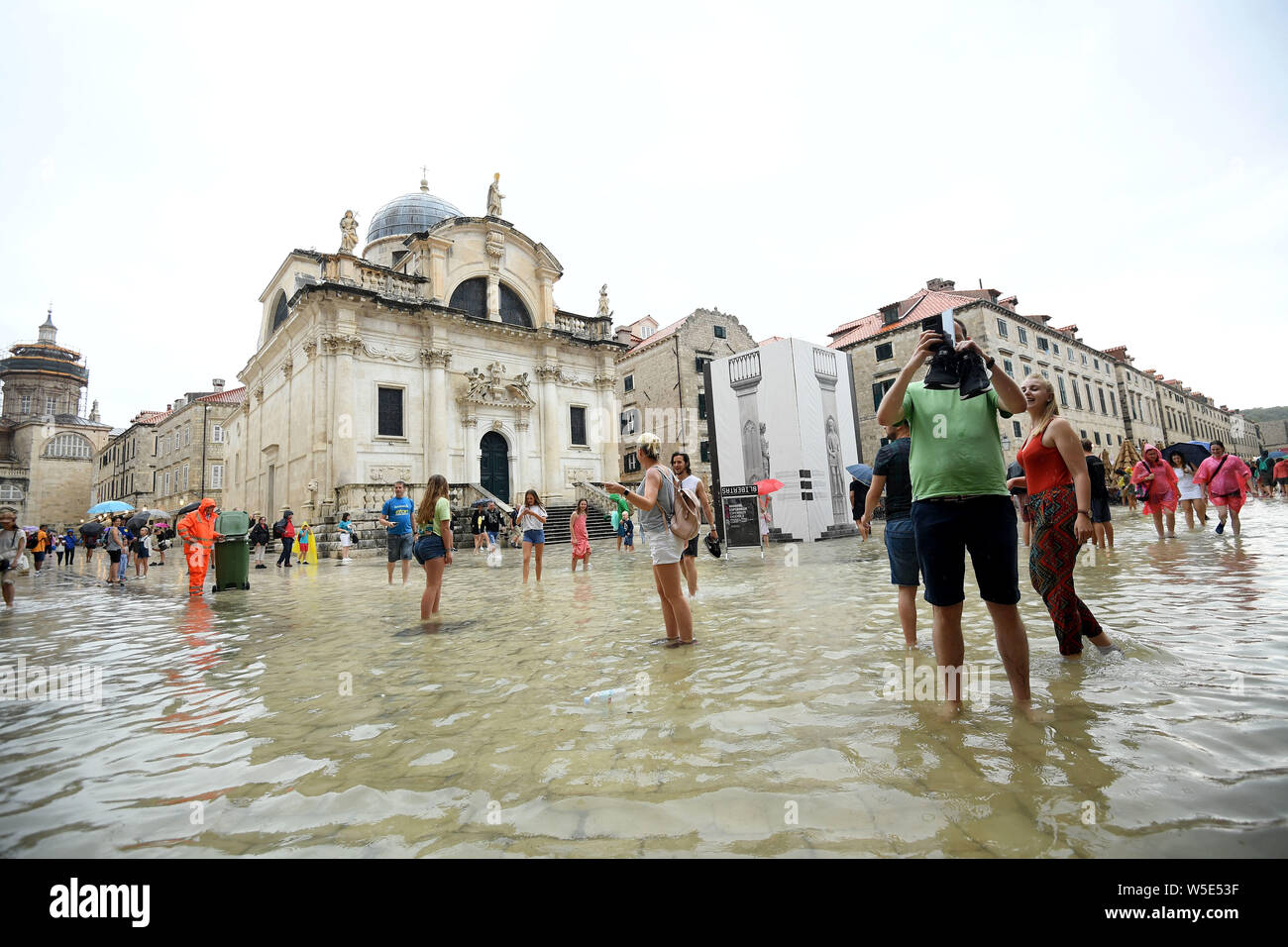 Dubrovnik, Croazia. 28 Luglio, 2019. La gente a piedi su una strada allagata della Città Vecchia di Dubrovnik, Croazia, il 28 luglio 2019. La famosa destinazione turistica è stata colpita da heavy rain e temporale di domenica. (Marko Lukunic/Pixsell via Xinhua) Credito: Xinhua/Alamy Live News Foto Stock