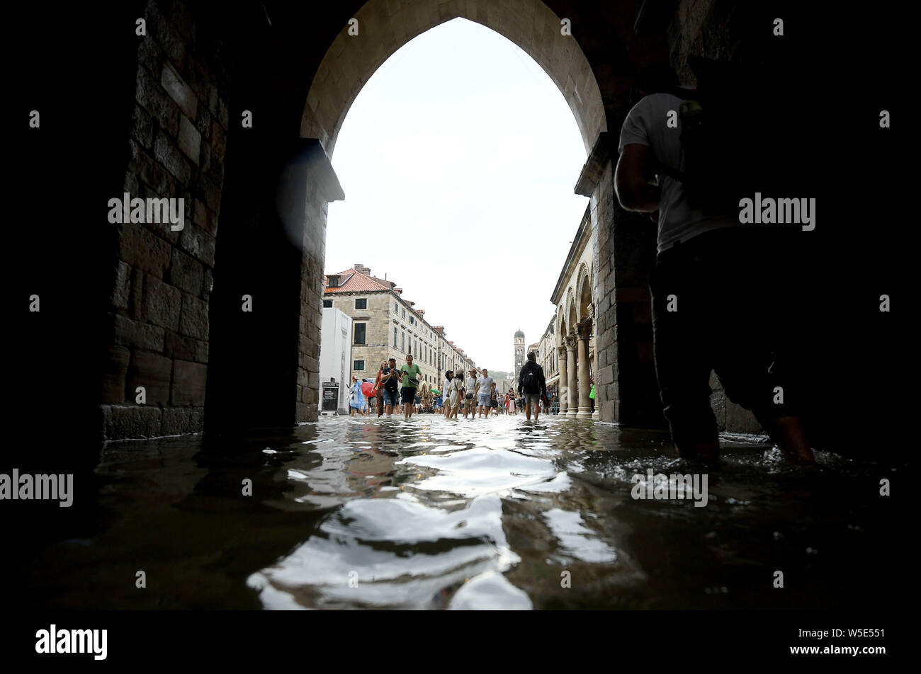 Dubrovnik, Croazia. 28 Luglio, 2019. La gente a piedi su una strada allagata della Città Vecchia di Dubrovnik, Croazia, il 28 luglio 2019. La famosa destinazione turistica è stata colpita da heavy rain e temporale di domenica. (Marko Lukunic/Pixsell via Xinhua) Credito: Xinhua/Alamy Live News Foto Stock
