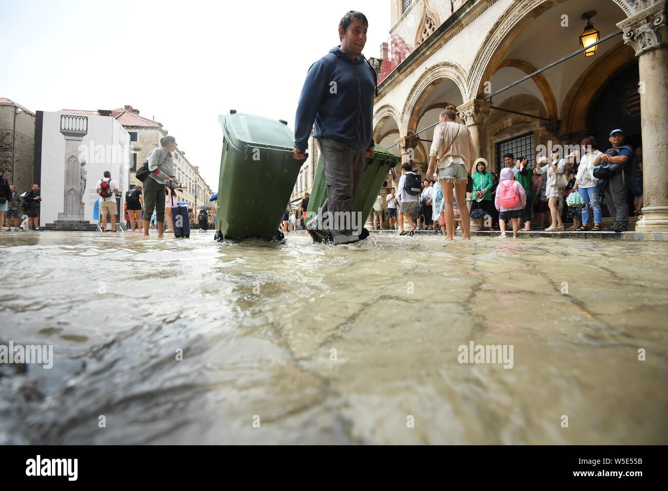 Dubrovnik, Croazia. 28 Luglio, 2019. La gente a piedi su una strada allagata della Città Vecchia di Dubrovnik, Croazia, il 28 luglio 2019. La famosa destinazione turistica è stata colpita da heavy rain e temporale di domenica. (Marko Lukunic/Pixsell via Xinhua) Credito: Xinhua/Alamy Live News Foto Stock