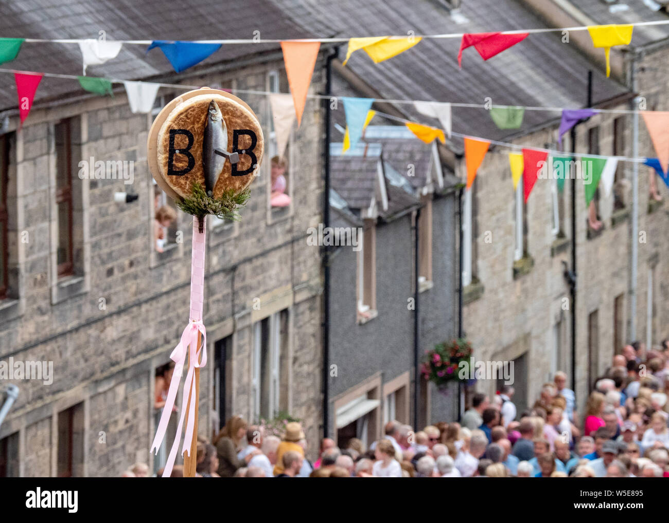 Langholm, Dumfries and Galloway, Scotland, Regno Unito. Il 26 luglio 2019. L'Orzo Bannock è tenuto aloft durante la camminata fino la Kirk Wynd. Foto Stock
