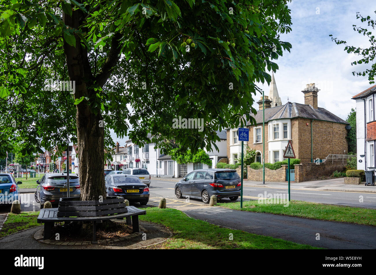 Un cavallo di castagno con una panca attorno accanto alla strada di Horton nel villaggio di Datchet, Berkshire, Regno Unito Foto Stock