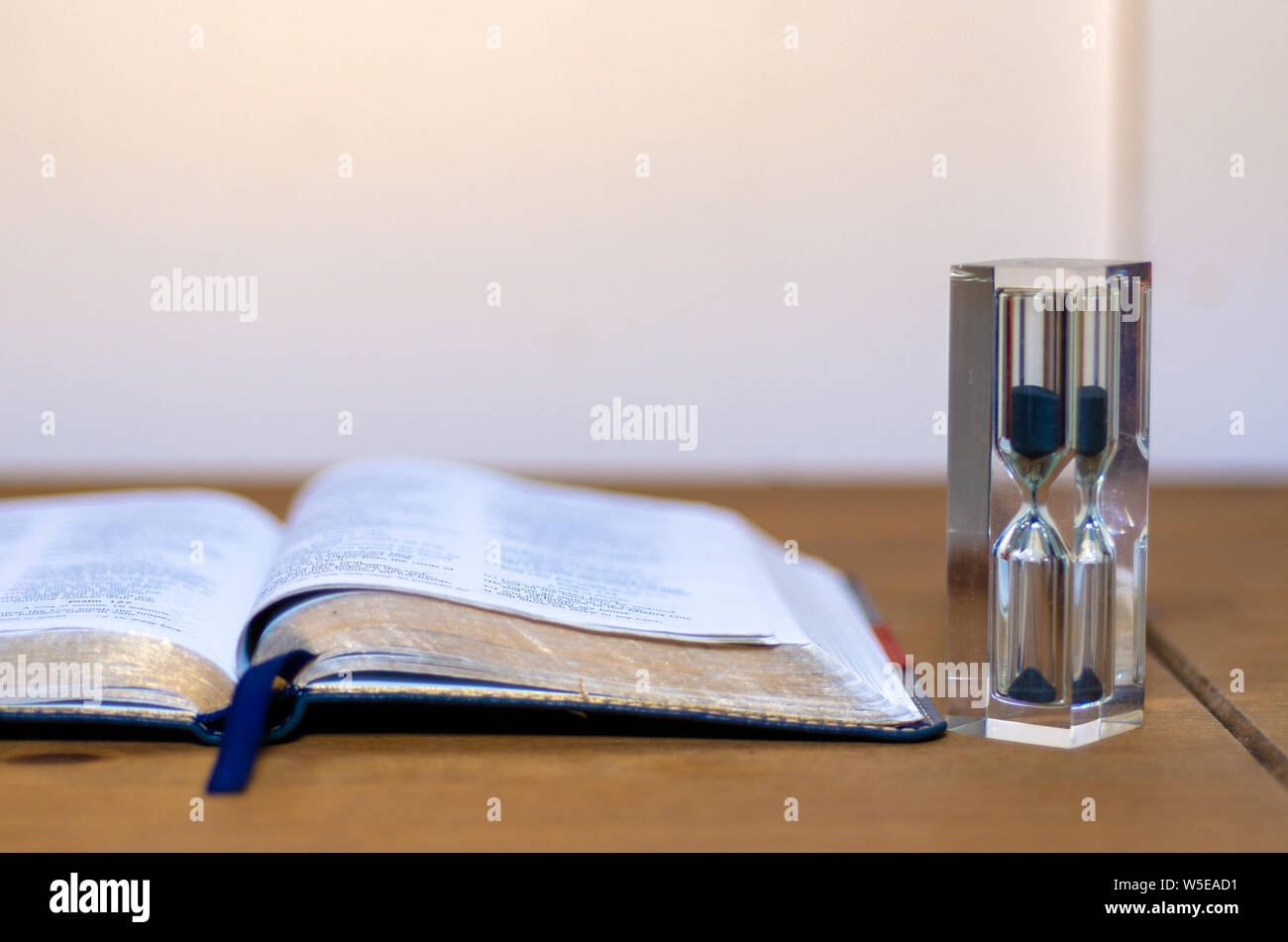 Una Bibbia aperta da una clessidra. È in grado di illustrare i temi del tempo. Foto Stock