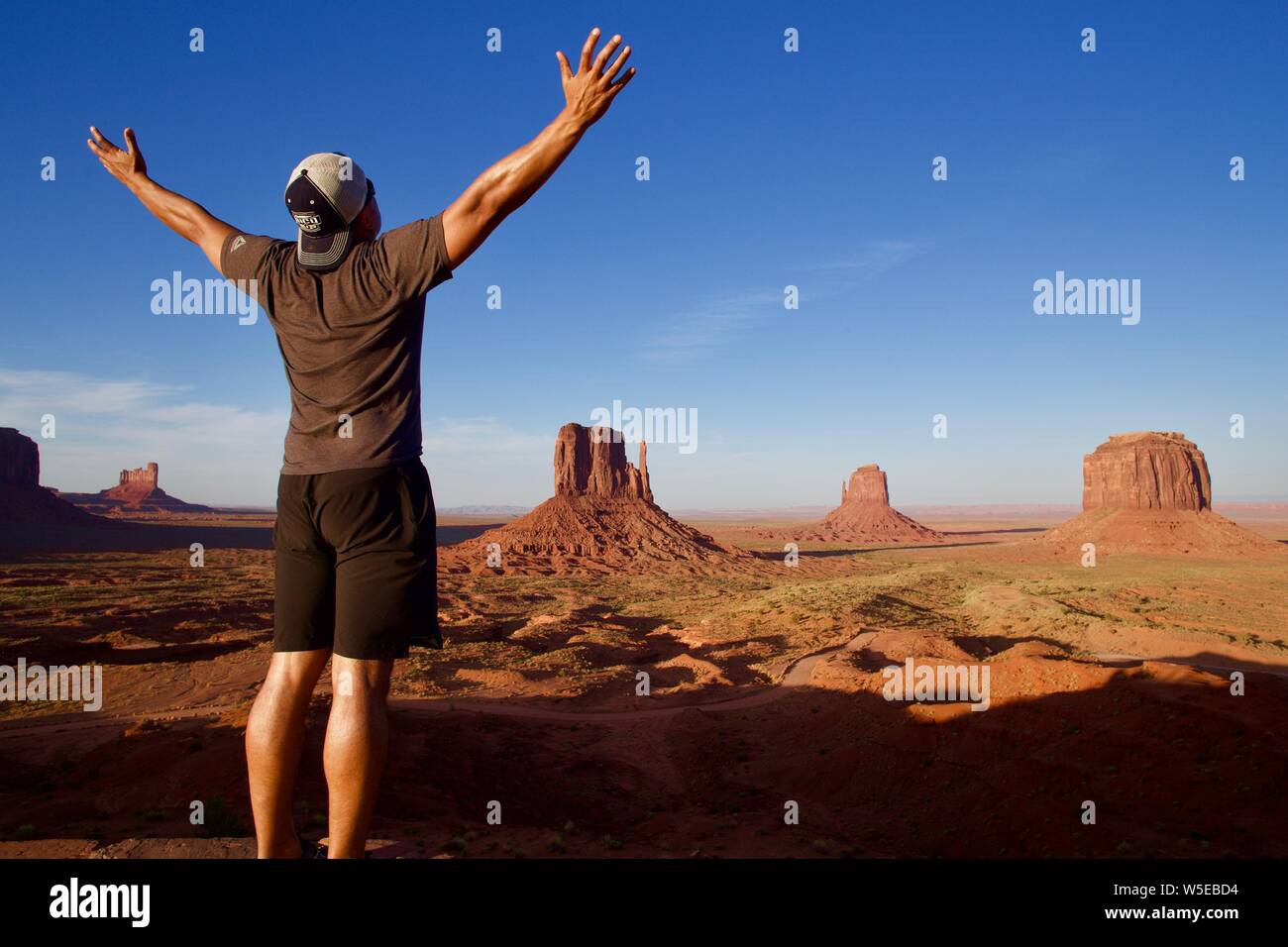 Uomo ispanico alla Monument Valley con le braccia in aria Foto Stock