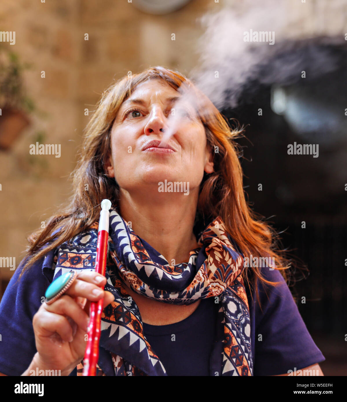 Una donna si brucia il fumo dal suo hookah tubo interno un ristorante in Amman, Giordania. Foto Stock