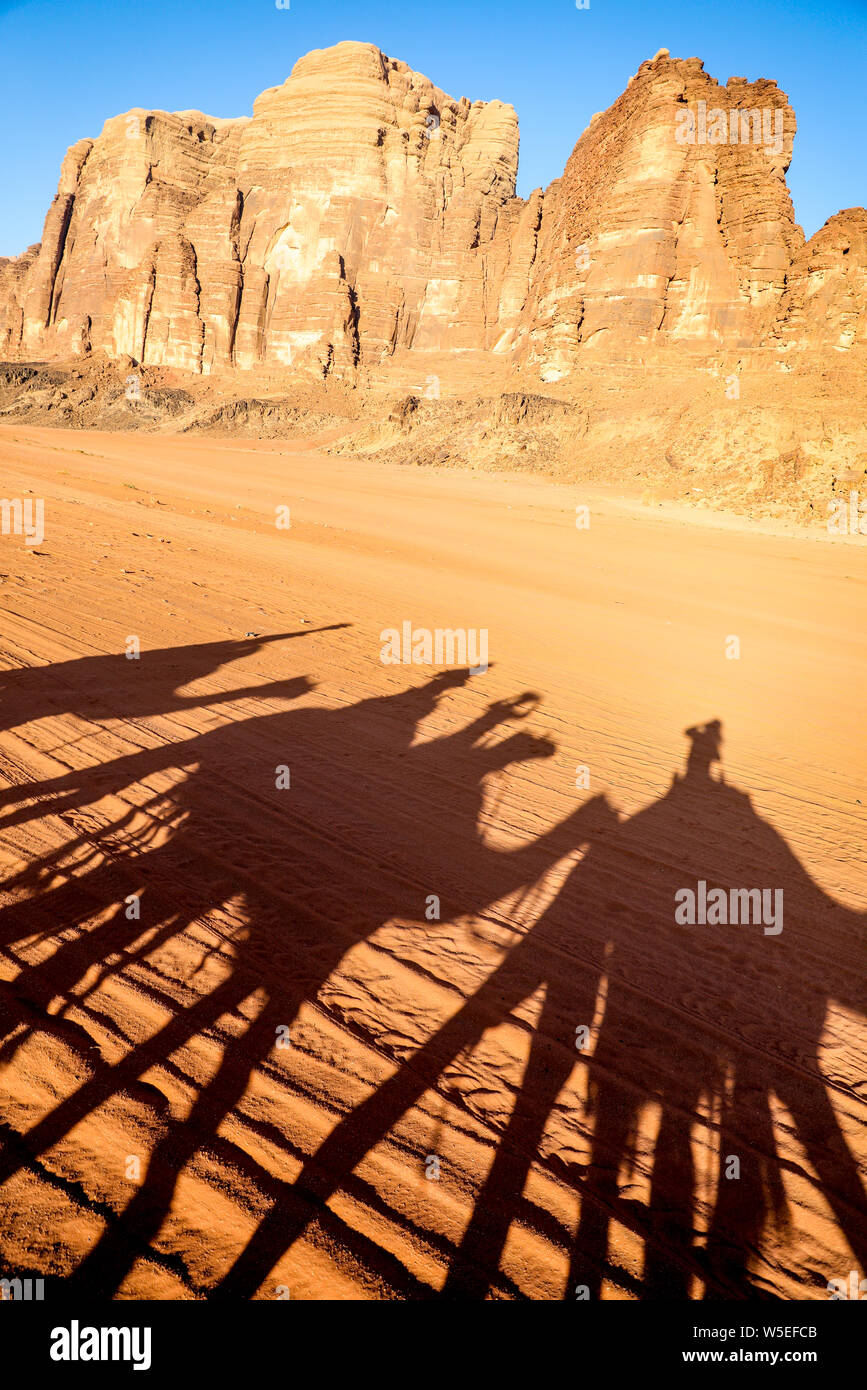 Silhouette di ombra di piloti sui cammelli che attraversano il deserto di Wadi Rum, Giordania. Foto Stock