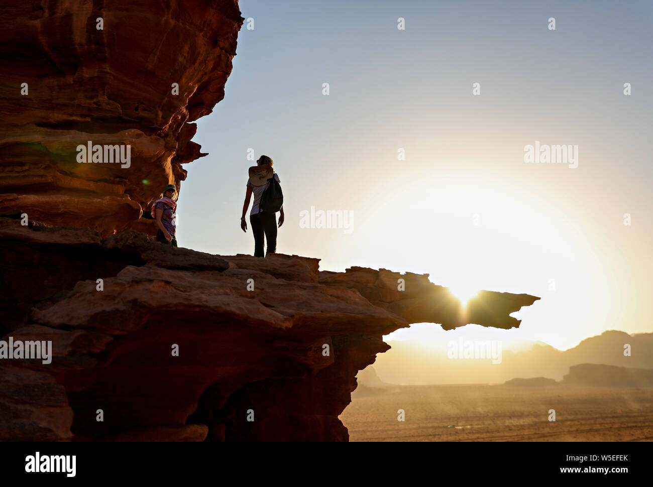 Una donna che cammina su un listello in Wadi Rum al tramonto. Foto Stock