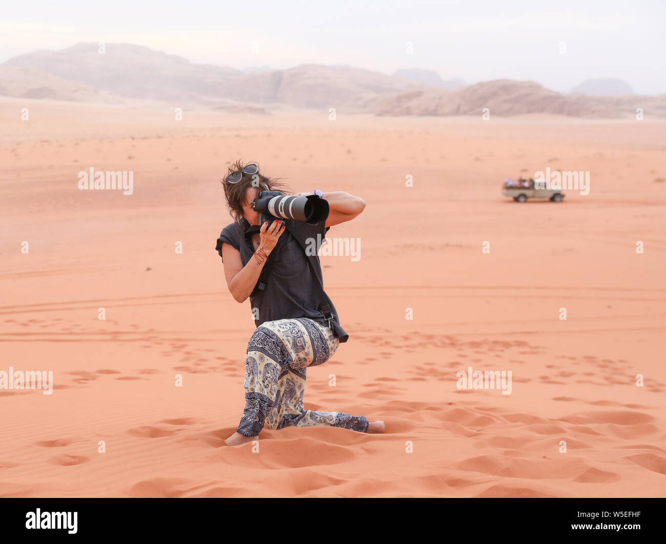 Un fotografo femmina consente di eseguire lo zoom avanti sulla posizione nel Wadi Rum, Giordania. Foto Stock