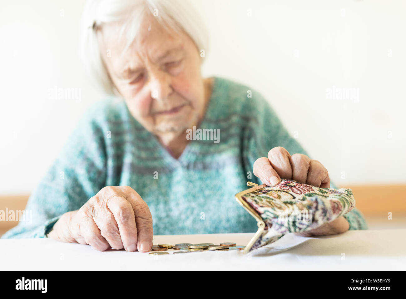 In questione anziani donna seduta al tavolo conteggiare denaro nel suo portafoglio. Foto Stock