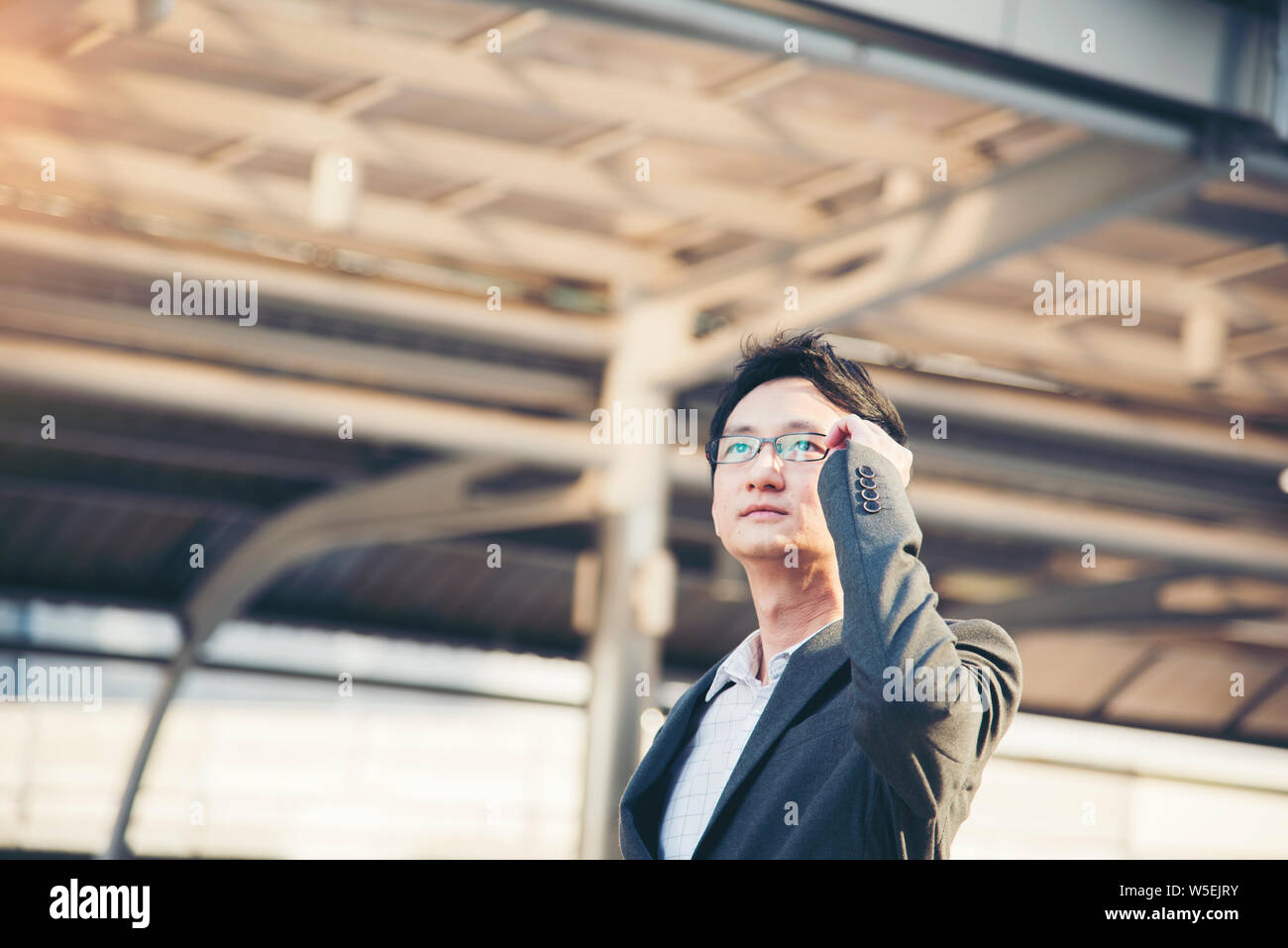Vista laterale di smart imprenditore fiducioso in piedi fuori guardare al futuro luminoso. Foto Stock
