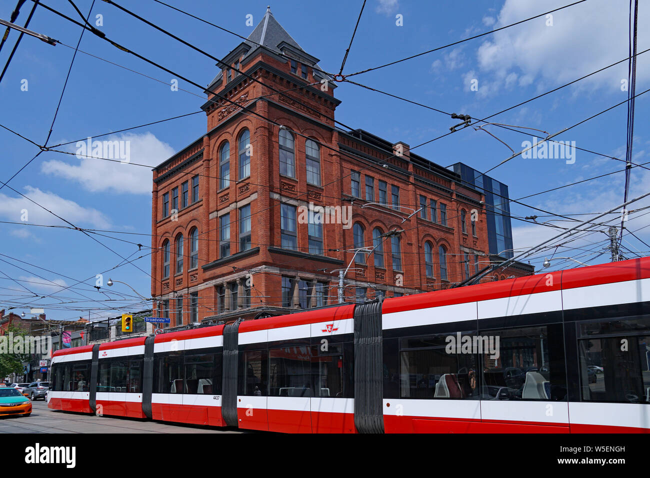 TORONTO - Luglio 2019: un lungo moderno articolando il tram passa davanti a un vecchio hotel vittoriano su Queen Street. Foto Stock