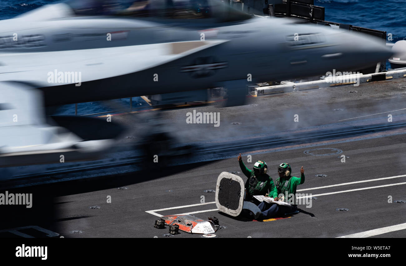 190722-N-ZM949-2095 OCEANO PACIFICO (24 luglio 2019) marinai dare il segnale per lanciare un messaggio E/A-18G Growler, assegnato al "Lupi grigi" di attacco elettronico Squadron (VAQ) 142, sul ponte di volo della portaerei USS Theodore Roosevelt CVN (71). Theodore Roosevelt sta conducendo le operazioni di routine nell'Oceano Pacifico orientale. (U.S. Foto di Marina di Massa lo specialista di comunicazione di terza classe Erick A. Parsons/rilasciato) Foto Stock