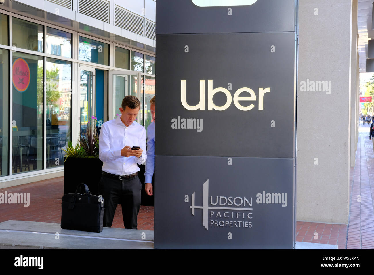 Segno Uber / logo a ride-condividendo la sede centrale della società a San Francisco in California con un uomo che guarda il suo telefono cellulare in background. Foto Stock