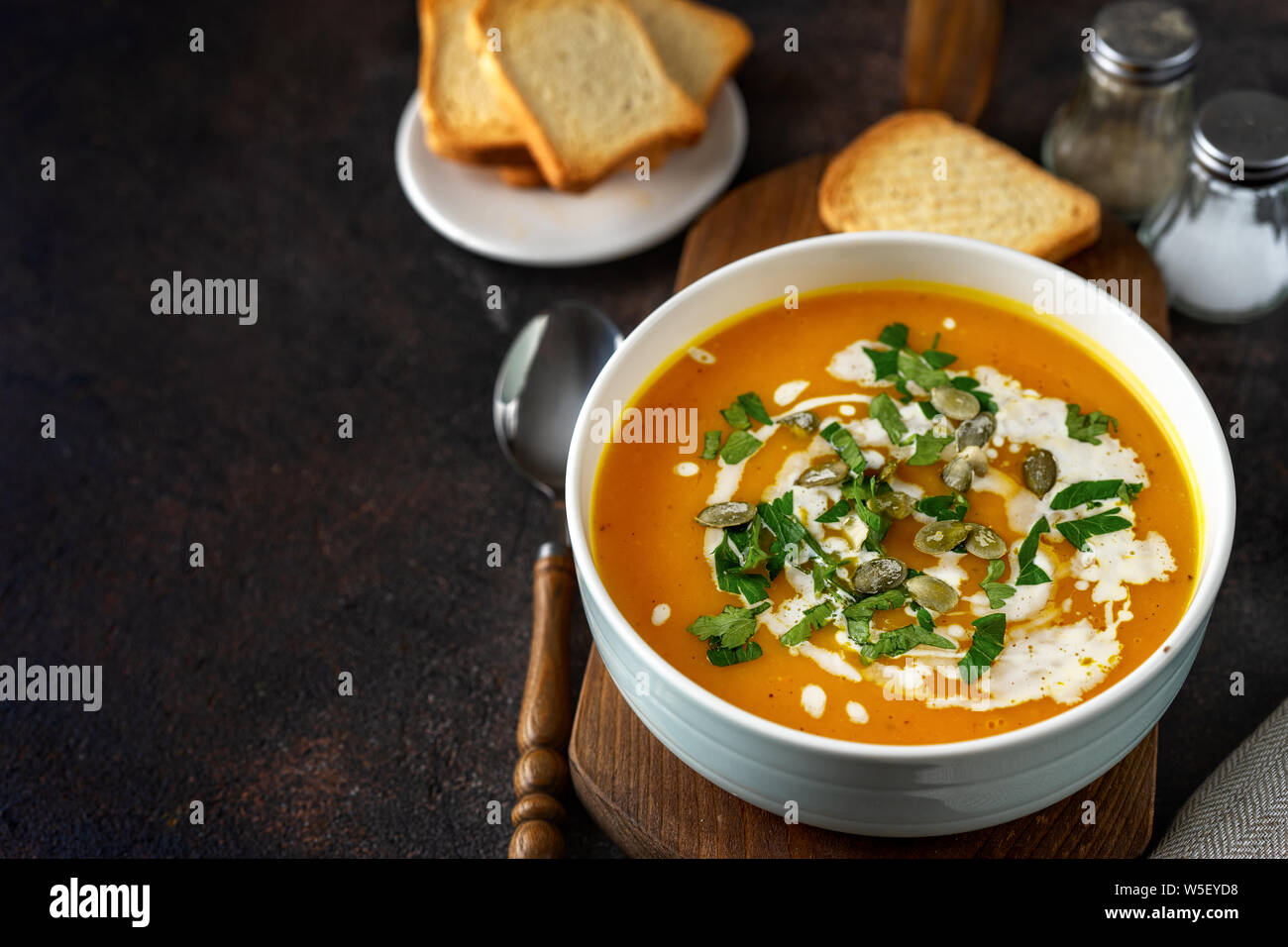 Zuppa di zucca con la panna e il prezzemolo scuro dello sfondo rustico Foto Stock