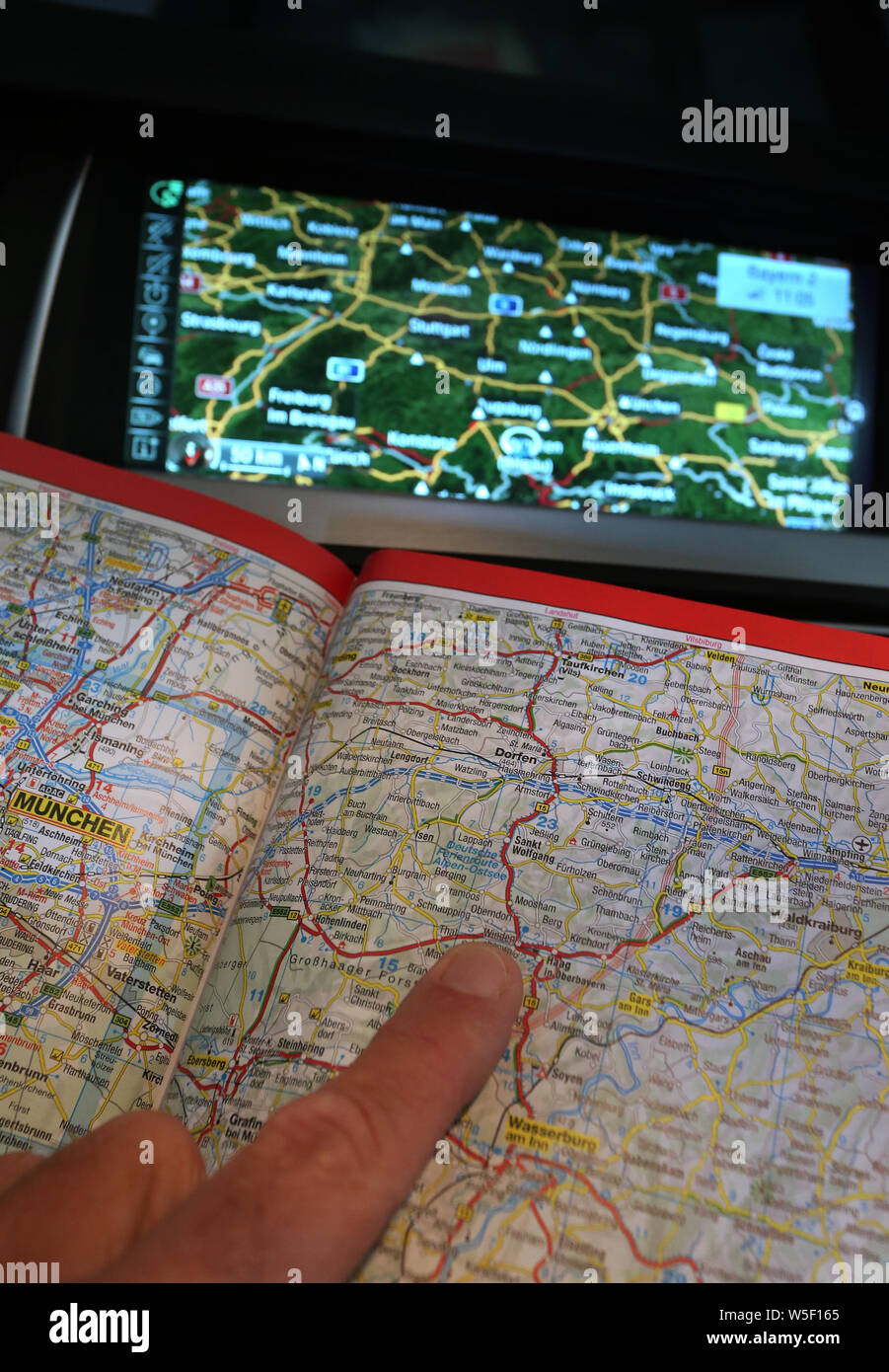 Kempten, Germania. Il 15 luglio 2019. Una strada aperta atlas può essere visto in una macchina davanti a un dispositivo di navigazione. In passato, piegato mostri di mappe stradali e mappe della città rigonfiata in fuori del vano portaoggetti. Co-piloti dovevano giocare timoniere. Oggi i telefoni cellulari e Navis hanno preso il posto di questo ruolo. (A dpa 'avete raggiunto la meta' - dalla scomparsa della mappa della città') Credito: Karl-Josef Hildenbrand/dpa/Alamy Live News Foto Stock