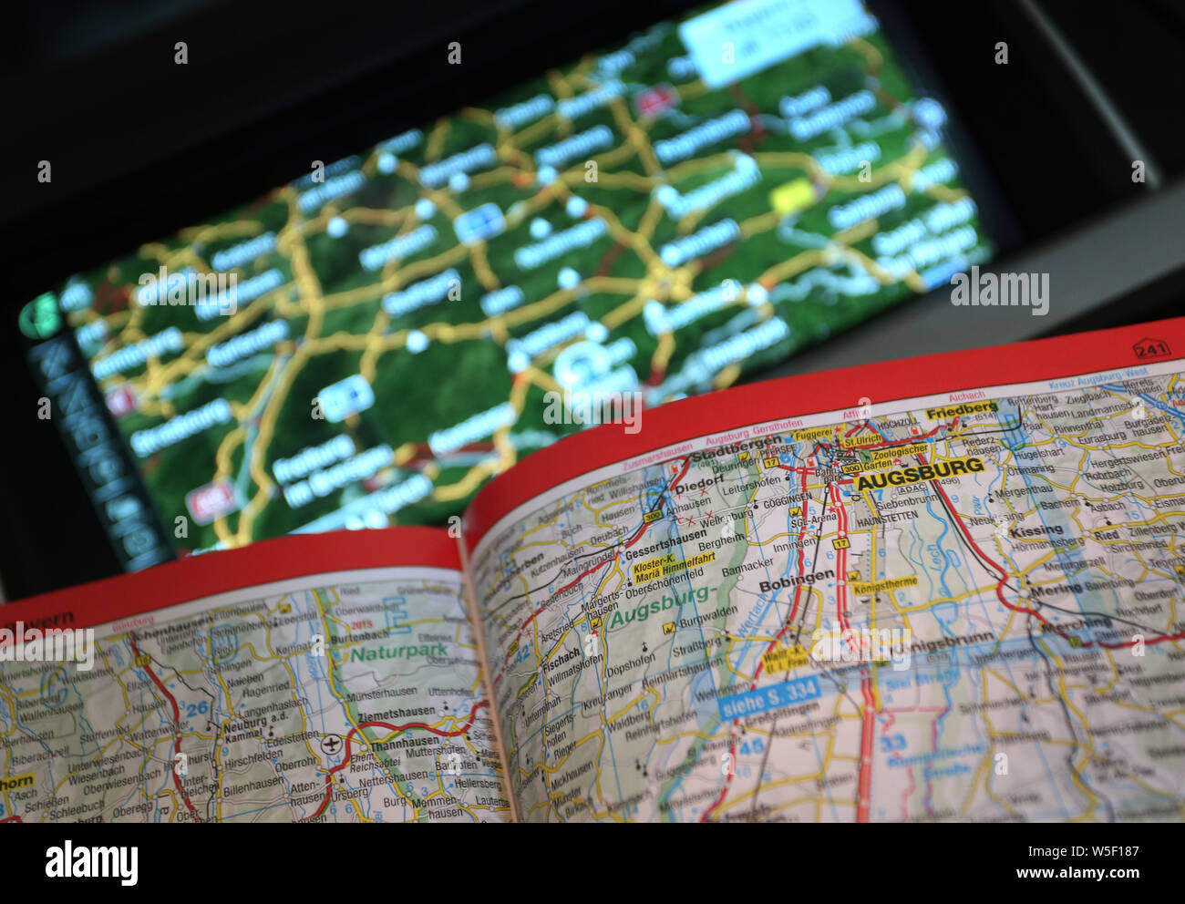 Kempten, Germania. Il 15 luglio 2019. Una strada aperta atlas può essere visto in una macchina davanti a un dispositivo di navigazione. In passato, piegato mostri di mappe stradali e mappe della città rigonfiata in fuori del vano portaoggetti. Co-piloti dovevano giocare timoniere. Oggi i telefoni cellulari e Navis hanno preso il posto di questo ruolo. (A dpa 'avete raggiunto la meta' - dalla scomparsa della mappa della città') Credito: Karl-Josef Hildenbrand/dpa/Alamy Live News Foto Stock